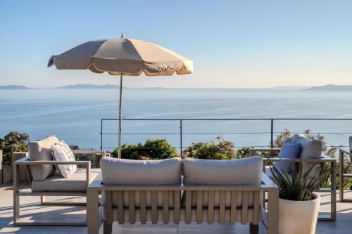 a patio with a table and chairs and an umbrella at Hôtel La Villa Douce in Rayol-Canadel-sur-Mer
