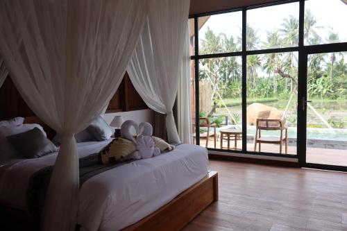 two stuffed animals sitting on a bed in a bedroom at Kose Ubud Villa in Ubud