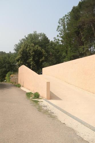 a brick wall next to a road with trees at le cosy Sainte Victoire in Peynier
