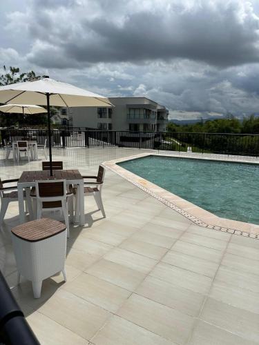 a patio with a table and an umbrella next to a pool at Nuevo Apartamento Campestre in El Caimo