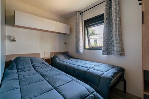 a bedroom with two blue beds and a window at Camping La Croix du Vieux Pont in Berny-Rivière