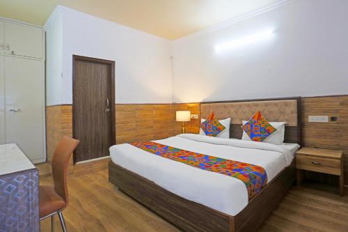 a hotel room with a large bed and a desk at FabExpress Vasant Villa - Near ILBS Hospital in New Delhi