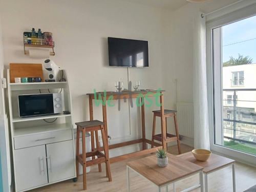un salon avec une télévision, une table et des chaises dans l'établissement Studio Modern Parking, à La Rochelle