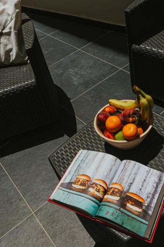 a bowl of fruit and a book on a table at Luma apartment - Sliema with Outdoor Space and BBQ Area in Sliema