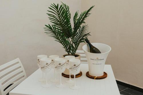 a white table with a potted plant and wine glasses at Luma apartment - Sliema with Outdoor Space and BBQ Area in Sliema