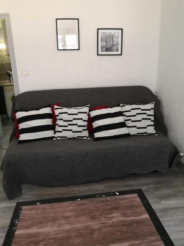 - un canapé noir avec des oreillers dans l'établissement joli sudio clim centre ville, à Avignon