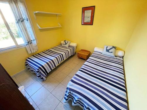 deux lits dans une chambre aux murs jaunes dans l'établissement Bas de villa proche de toute commodités, à Saint-Mandrier-sur-Mer