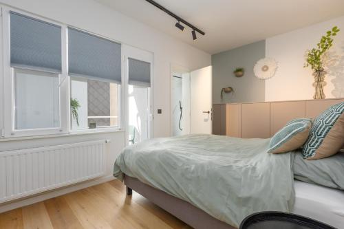 a bedroom with a bed and two windows at Beau Soleil in Ostend