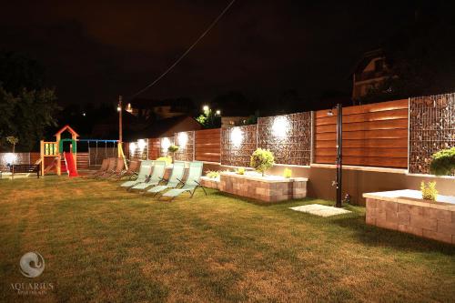 a backyard with chairs and a playground at night at Aquarius Apartments in Miskolctapolca