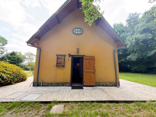 a small yellow building with a black door at Maison au calme à la campagne in Les Bottereaux