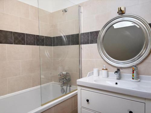 a bathroom with a sink and a mirror and a tub at Maison au calme à la campagne in Les Bottereaux