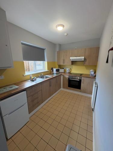 a kitchen with yellow walls and wooden cabinets at Rathlin Apartment - 2 Bedroom with Hot Tub in Ballycastle
