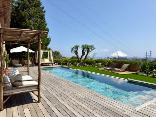 une piscine avec une terrasse en bois à côté d'une maison dans l'établissement La Sapinière - SCLS Rentals, à Mougins
