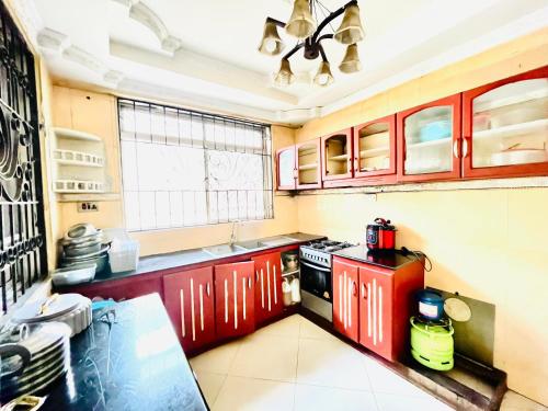 cocina con armarios rojos y fogones en V & V BnB, en Dar es Salaam