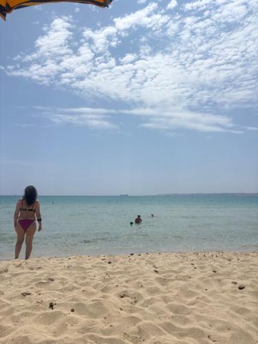 a woman in a bikini standing on the beach at Casa vacanza da Sandro in Priolo Gargallo