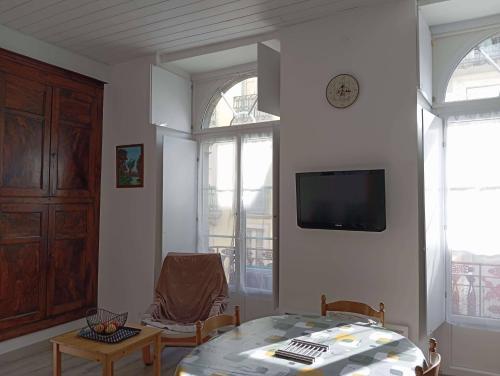 un salon avec une table et une télévision dans l'établissement Appartement 3Etoiles Plein centre ville Cauterets avec balcon, à Cauterets