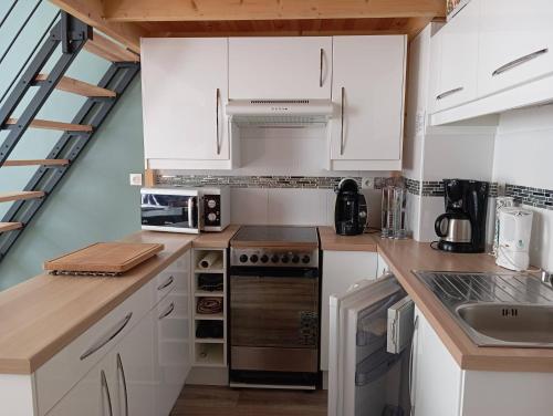 une cuisine avec des armoires blanches et un four à plaques de cuisson dans l'établissement Appartement 3Etoiles Plein centre ville Cauterets avec balcon, à Cauterets