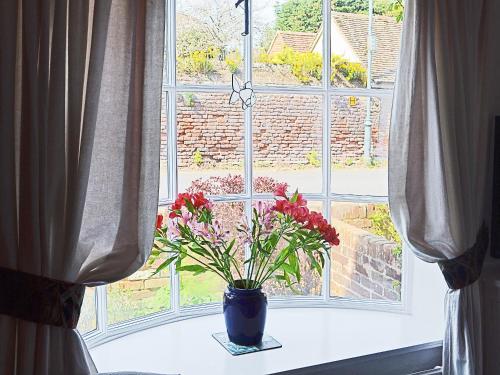 un vase avec des fleurs assis sur un rebord de fenêtre dans l'établissement Bow Cottage, à Fordwich