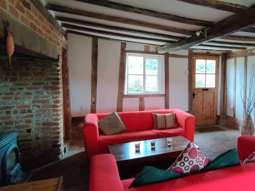 un soggiorno con mobili rossi e un muro di mattoni di Burnt House Cottage a Barking