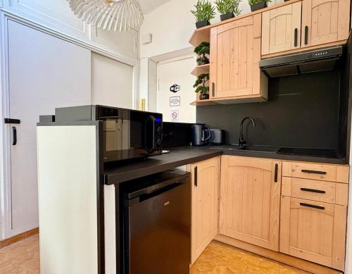 une cuisine avec des armoires en bois et un réfrigérateur noir dans l'établissement Port 1BR Flat with Terrace, à Nice