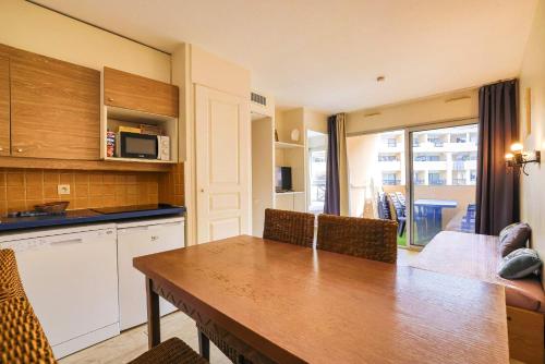 une cuisine avec une table et des chaises et un micro-ondes dans l'établissement Le Cannes Beach 447 - Confort & soleil - Piscine, à Cannes
