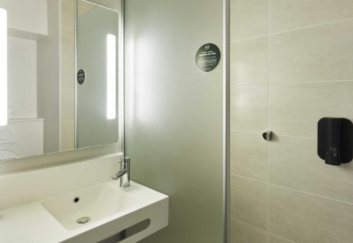 a white bathroom with a sink and a shower at B&B HOTEL Paris Est Bobigny Université in Bobigny