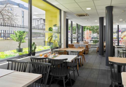 a restaurant with tables and chairs and large windows at B&B HOTEL Paris Est Bobigny Université in Bobigny