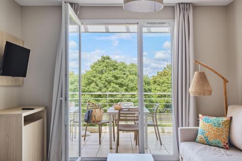 d'un salon avec une porte coulissante en verre s'ouvrant sur un balcon. dans l'établissement Résidence Odalys Les Océanides, à La Londe-les-Maures