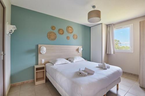 a bedroom with a large white bed and a window at Résidence Odalys Les Océanides in La Londe-les-Maures