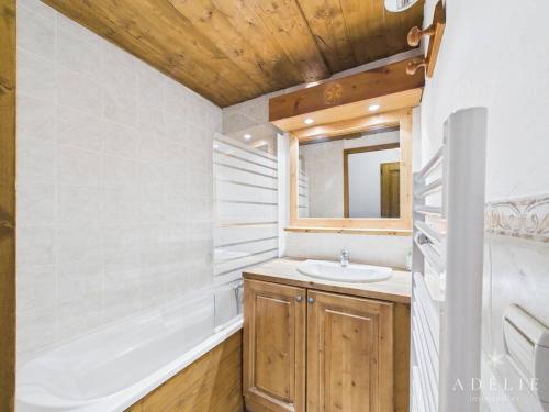 een badkamer met een wastafel, een bad en een spiegel bij Appartement 4 Pièces au Centre de la Station, Proche Remontées Mécaniques, Parking et Balcon Est - FR-1-398-521 in La Rosière