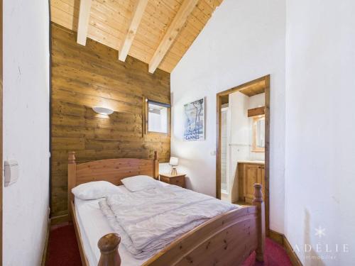 een slaapkamer met een bed met een houten muur bij Appartement 4 Pièces au Centre de la Station, Proche Remontées Mécaniques, Parking et Balcon Est - FR-1-398-521 in La Rosière