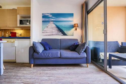 un salon avec un canapé bleu dans une cuisine dans l'établissement Le Cannes Beach 380 - lumineux balcon & piscine, à Cannes