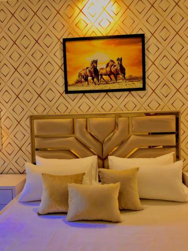 ein Schlafzimmer mit einem Bett und einem Gemälde an der Wand in der Unterkunft Luxury Family Apartment in Islamabad