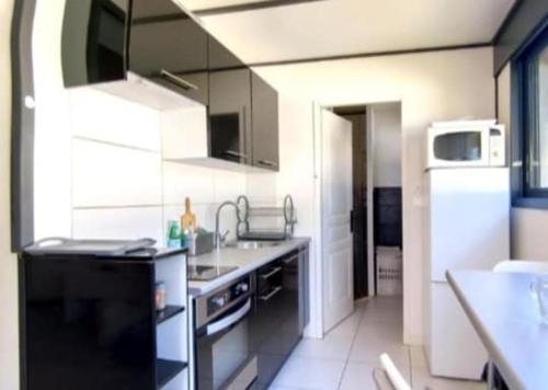 une petite cuisine avec un évier et une cuisinière dans l'établissement Petite maison cosy au calme, à Royan