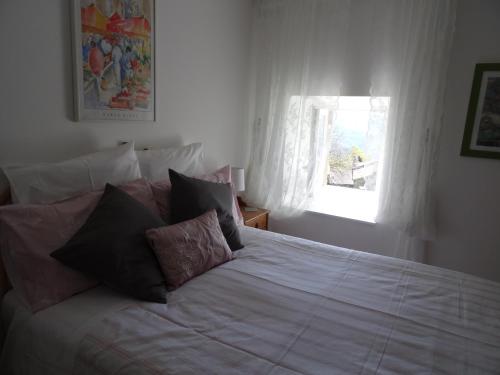 Un dormitorio con una cama blanca con almohadas y una ventana en Au Pied de la Roche, en Roche-en-Régnier