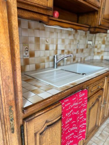 - un comptoir de cuisine avec un évier et une serviette rouge dans l'établissement Chez Colette, maison agréable, à Villebernier