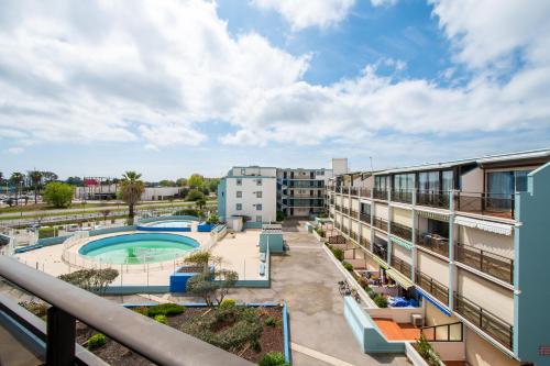 un patio d'appartement avec piscine et bâtiments dans l'établissement Studio cabine cosy Lagon Bleu Piscine, clim, parking, wifi inclus, au Grau-du-Roi