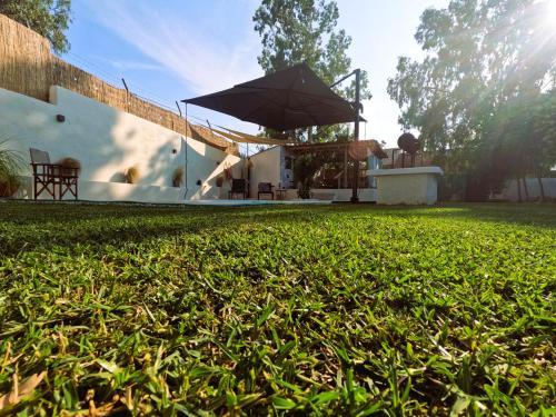 a house with an umbrella and a grass yard at Cozy Mama Evas Homestay with Pool and Garden for Groups of 4 in Kirás Vrísi