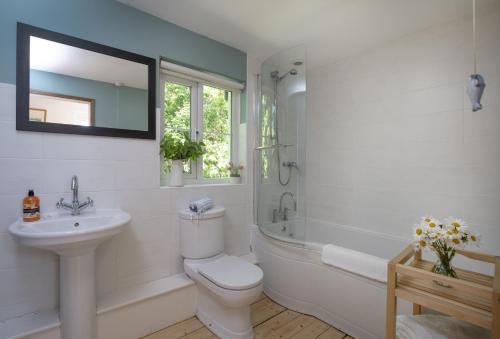 a bathroom with a sink and a toilet and a bath tub at Berry Cottage in Croyde