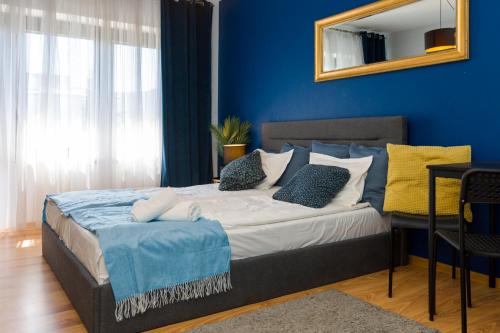 a bedroom with a bed with blue walls and a mirror at NaNoc - noclegi obok lubelskich szpitali i centrum Lublina in Lublin