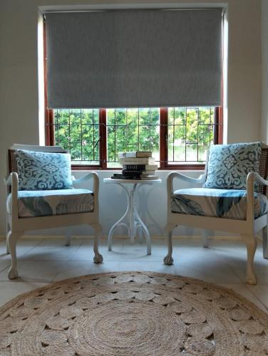 two chairs and a table in a room with a window at Charming Cottage in Prime Location in Gqeberha
