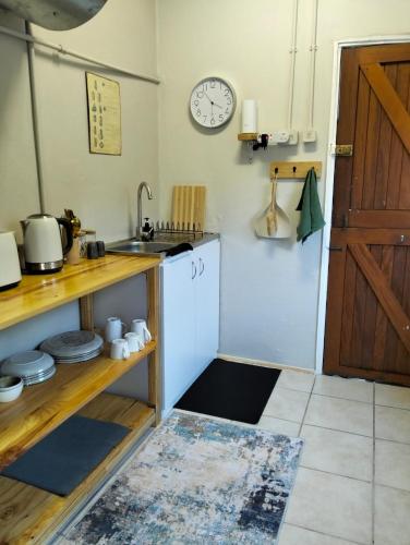 a kitchen with a sink and a clock on the wall at Charming Cottage in Prime Location in Gqeberha