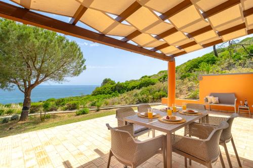 een terras met een tafel en stoelen en de oceaan bij The Oceanfront Villa Luz VR114 in Luz