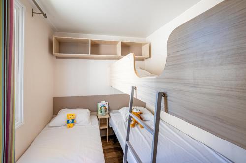 deux lits dans une petite pièce aux murs blancs dans l'établissement Camping les bo-bains, à Badefols-sur-Dordogne