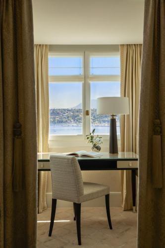 a desk with a lamp and a chair in front of a window at The Woodward - Auberge Collection in Geneva