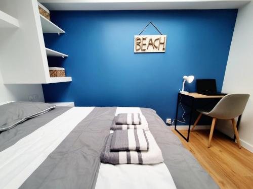 - une chambre avec un lit, un bureau et un mur bleu dans l'établissement MOLENE I Studio Neuf I Parking Gratuit I Proche Mer I Wifi haut débit, à Saint-Brieuc