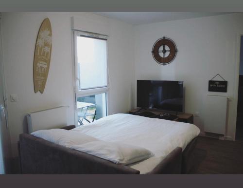 une chambre avec un lit, une télévision et une fenêtre dans l'établissement T2 Cosy avec Terrasse et Jardinet, à La Rochelle