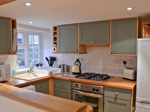 a kitchen with green cabinets and a stove top oven at Sweet Pea Cottage in Heacham