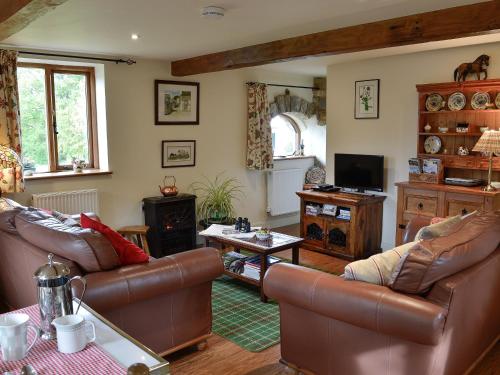 ein Wohnzimmer mit Ledermöbeln und einem TV in der Unterkunft Bryn Dedwydd Cottage in Llanferres
