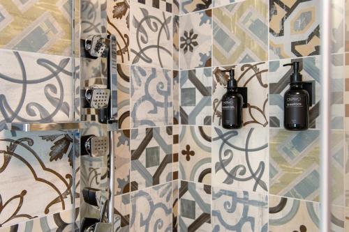 a bathroom with a tile wall with two bottles on it at La chambre d'Emilie - romantic room in Valtournenche